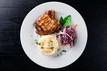 Fried pork fillet steak with mashed potatoes and salad of fresh cabbage, carrots, onions.