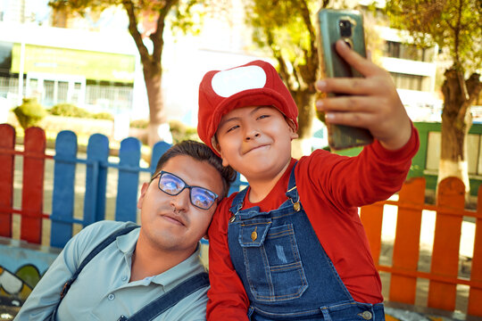 latin father and son taking a selfie together in an outdoor park in video game clothes in the city of la paz Bolivia.