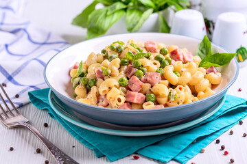 Homemade pasta with green peas and ham close up.