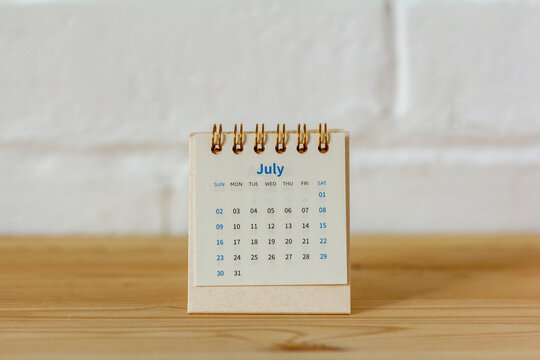 Desktop calendar for July 2023 on the table with a space to copy.