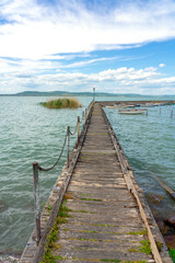 wooden pier in Balatonlelle with colorful boats on lake Balaton blue sky and water
