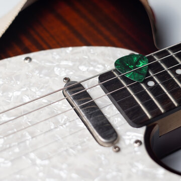 Green Guitar Pick in Strings of Electric Guitar