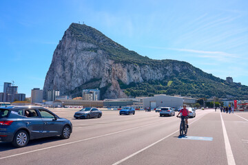 happy senior woman cycling with her electric mountain bike on the airport fairway below the Rock of Gibraltar, Andalusia, Spain