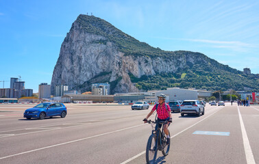 happy senior woman cycling with her electric mountain bike on the airport fairway below the Rock of...