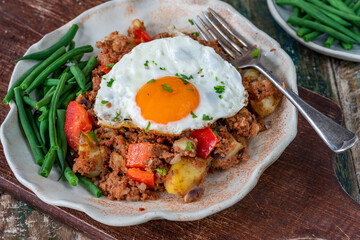 Corned beef hash with fried egg and green beans