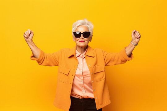 grandmother with sunglasses doing poses on a studio with yellow background