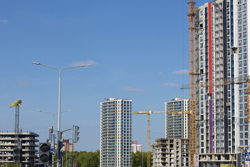 Construction site. Reinforced concrete frames of multi-storey buildings and construction cranes. Finished houses nearby. Against the background of the blue sky.