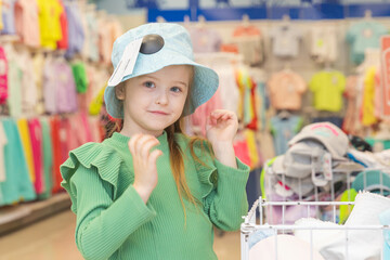 Cute Little Girl Picking her Own Clothes in Fashion Store. Toddler having freedom of choice deciding what to wear independently dressing herself with style expressing fashion sense