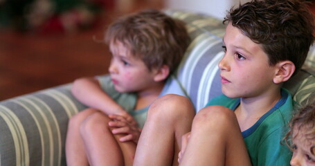Kids at home sofa watching TV screen at night