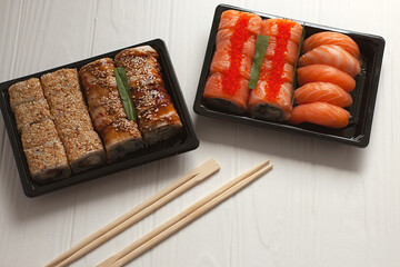 Sushi and Sashimi rolls on a black stone slatter. Fresh made Sushi set with salmon, prawns, wasabi and ginger. 