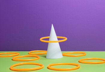 Accuracy concept - Orange ring over white cone, green surface, purple background, other rings...