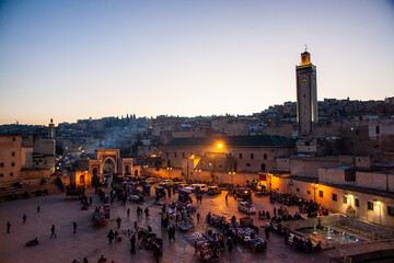 Arabic square Rcif in Fes in Morocco at sunset. People in market and street food.  