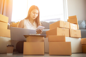 woman checking package of goods from customer online order is alone in her home office as she is an SME entrepreneur and uses her phone and tablet to market online. concept online sales business