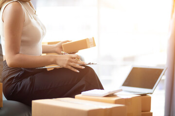 small sme entrepreneur is packing products into parcel boxes in preparation for transporting them...