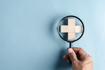 Health insurance healthcare medical concept. Hand people holding Magnifier focus to plus symbol wooden block, health and access to welfare health concept