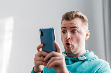 Shocked and surprised asian man looking smartphone. Close up portrait.
