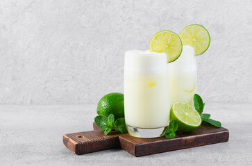 Brazilian Lemonade, Refreshing Creamy Lemonade or Limeade with Lime Slices and Mint on Grey Background - obrazy, fototapety, plakaty