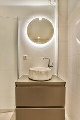 Fototapeta na wymiar a bathroom with a sink and mirror on the wall next to it is an illuminated round light above the sink
