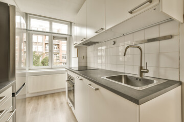 a kitchen area with white cabinets and black counter tops in front of an open window looking out...
