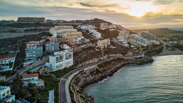 Bustling city on a cliff overlooking the ocean. Aerial view of the layout and architecture, high-rise buildings, busy streets, boats, and greenery.