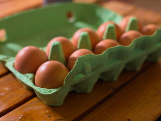 Eggs in a green box on wooden table - obrazy, fototapety, plakaty