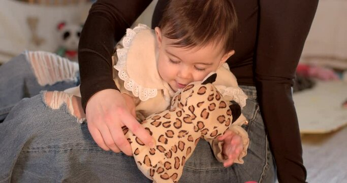 Portrait of a toddler child, a toy in her hands, she looks into the camera. Bites the tissue of an object with his teeth. period of tooth growth. Black eyes.