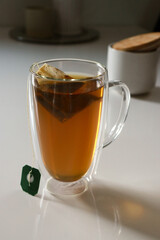 close up of a glas cup of black tea, flowers in background 