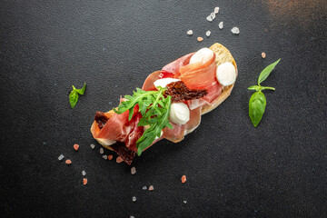 Tasty bruschetta with ham on a dark background. banner, menu, recipe place for text, top view