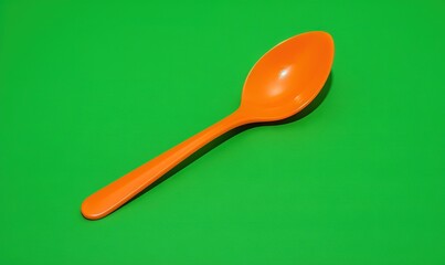  an orange spoon sitting on top of a green table top.  generative ai