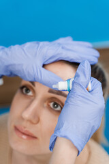 Ophthalmologist drips eye drops into eyes of woman patient for treatment of dry eyes syndrome.