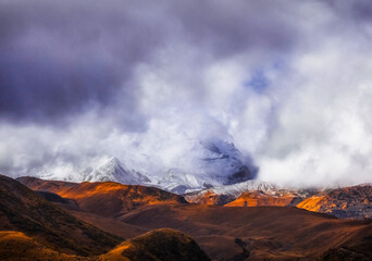 Clouds cover slopes of Kazbegi mountain during sunset time in Georgia Caucasus