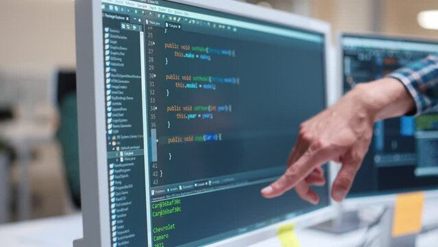 Close-up of screen where visible creating or programming software. Engineers finger pointing at monitor. Developing web sites, programs or games on computer. Working on Desktop. Using PC. Technology.