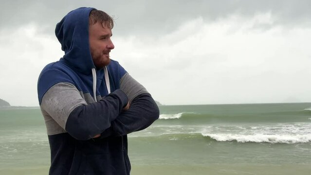 Portrait of unhappy depressed frozen trembling guy, young shivering from cold sad upset man on the sea beach, suffering from bad weather on summer vacation 