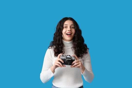 Teenage girl with photo camera on blue background