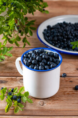 White bowl cup with fresh ripe blueberries on wooden table