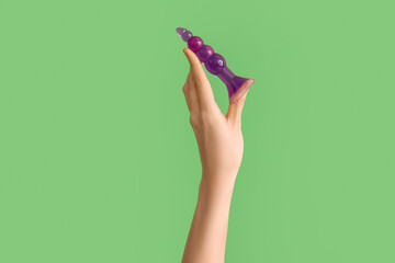 Woman with anal plug from sex shop on green background
