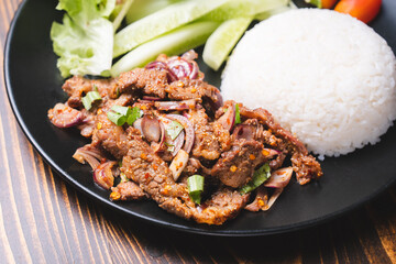 Spicy Grilled Beef or pork and chicken Thai style salad (Red onion, Spring onion, Rice powder, Lettuce Chili powder )in a bowl with rice, called as Nam Tok, Jaew dipping sauce and vegetables