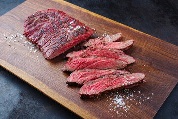 Traditional American barbecue bavette steak with salt and pepper served as close-up on a wooden design board