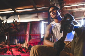 Obraz na płótnie Canvas Portrait of a confident Asian male mechanic holding wrench at garage, Auto mechanic standing against a car in a repair garage for using in business of car, expertise mechanic working in automobile
