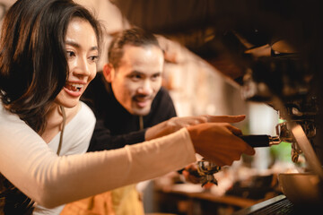 Smiling young female barista with male colleague in apron preparing coffee while holding filter and equipment while preparing beverage for customer in modern cafe