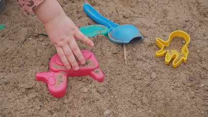 Fototapeta na wymiar Caucasian Child Playing in Sandbox with Plastic Sand Molds 