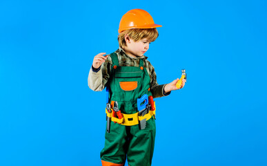 Boy in safety helmet and toolbelt with hammer. Child in builder uniform with tools for repair....