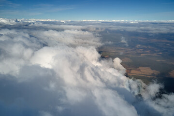 Aerial view from airplane window at high altitude of earth covered with puffy cumulus clouds...