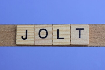 word jolt made from wooden gray letters lies on a blue background