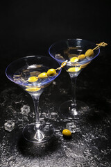 Glasses of tasty martini with olives on dark background