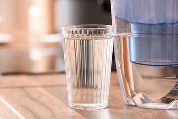 Filter jug and glass of water on kitchen counter, closeup