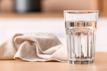Glass of water and napkin on table in kitchen