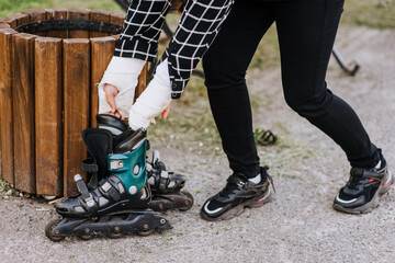 A girl, a woman athlete with broken arms in a cast, throws out roller skates on a trash can after an injury in sports. Close-up photography, portrait, end of career.