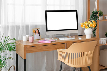 Comfortable workplace with modern PC and narcissus flowers near window