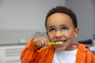 African-american boy looking involved while brushing his teeth